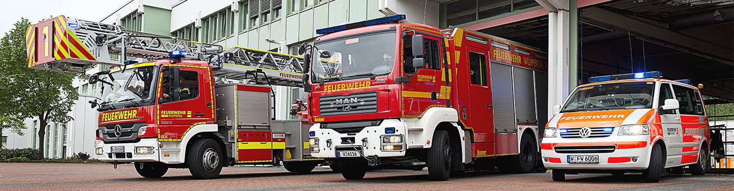 Drei Einsatzfahrzeuge der Feuerwehr stehen auf dem Hof der Wache.