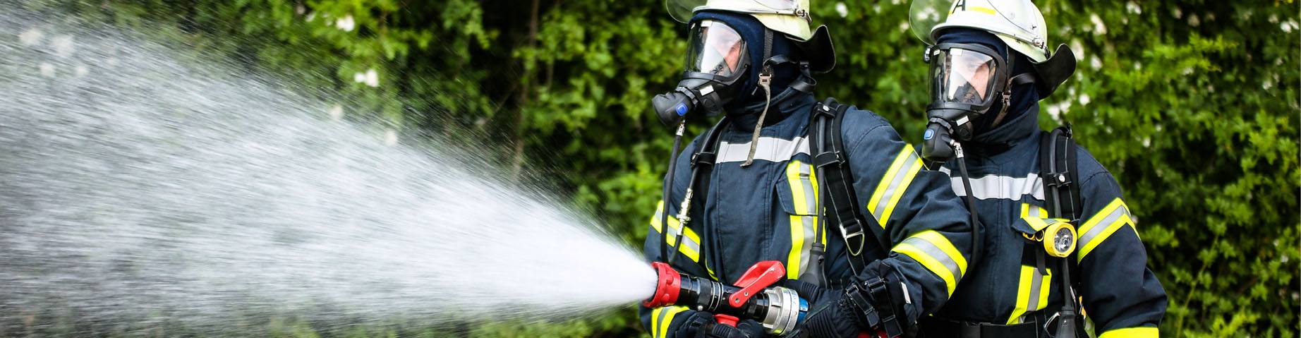 Zwei Mitglieder der Freiwilligen Feuerwehr bei einem Löschangriff.