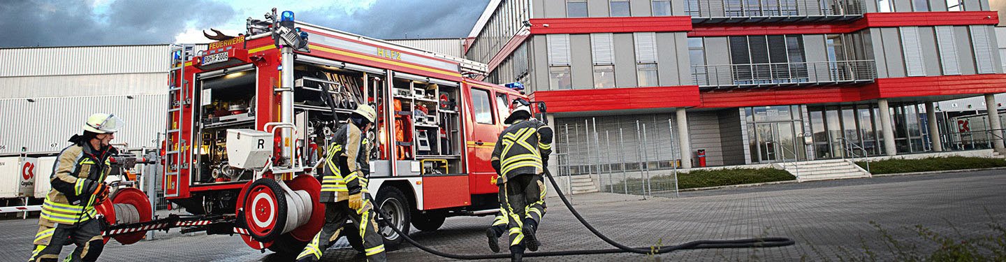 Ein Einsatztrupp der Feuerwehr macht sich vor einem Bürogebäude bereit für Löscharbeiten.